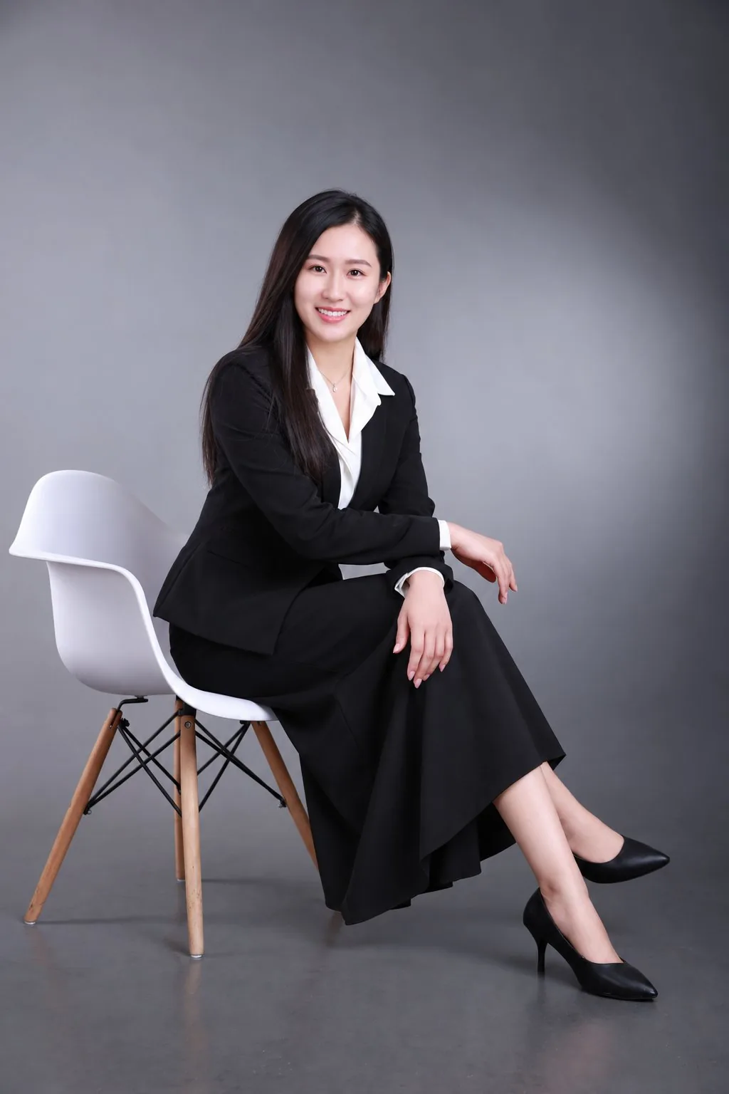 身穿西裝坐在白色椅子的女性形象照